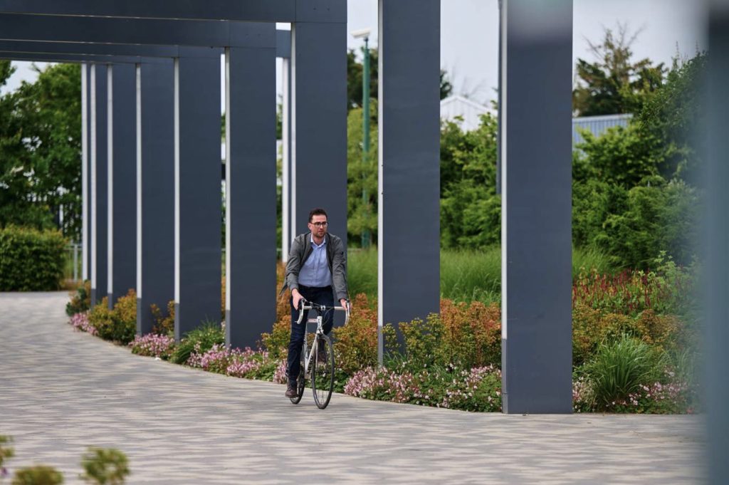 Man cycling through the plaza at Cambridge Science Park